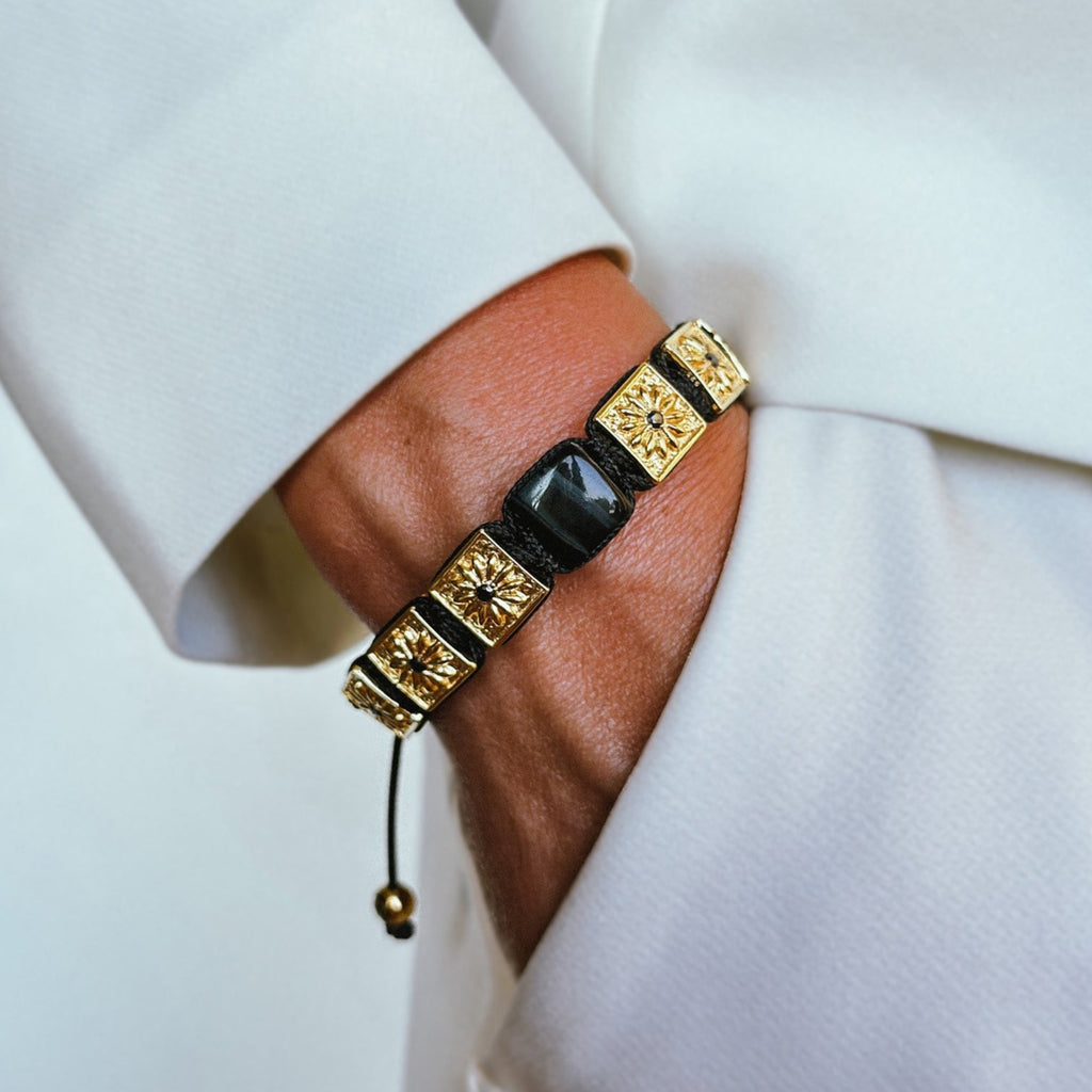 woman with white outfit wearing black and gold macrame bracelet with black tiger eye - the guardian 