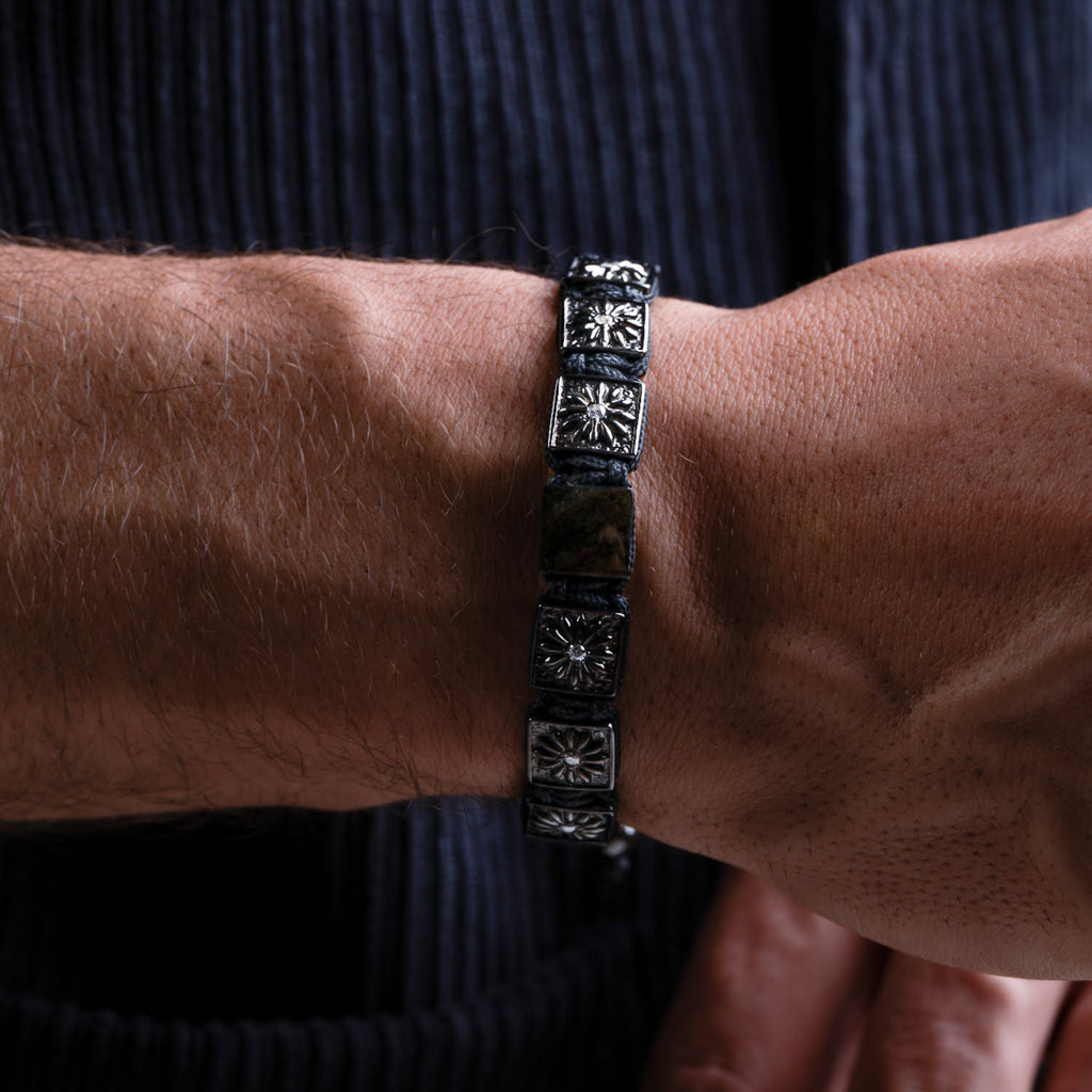 Close-up of a person's wrist wearing a black bracelet with silver designs.