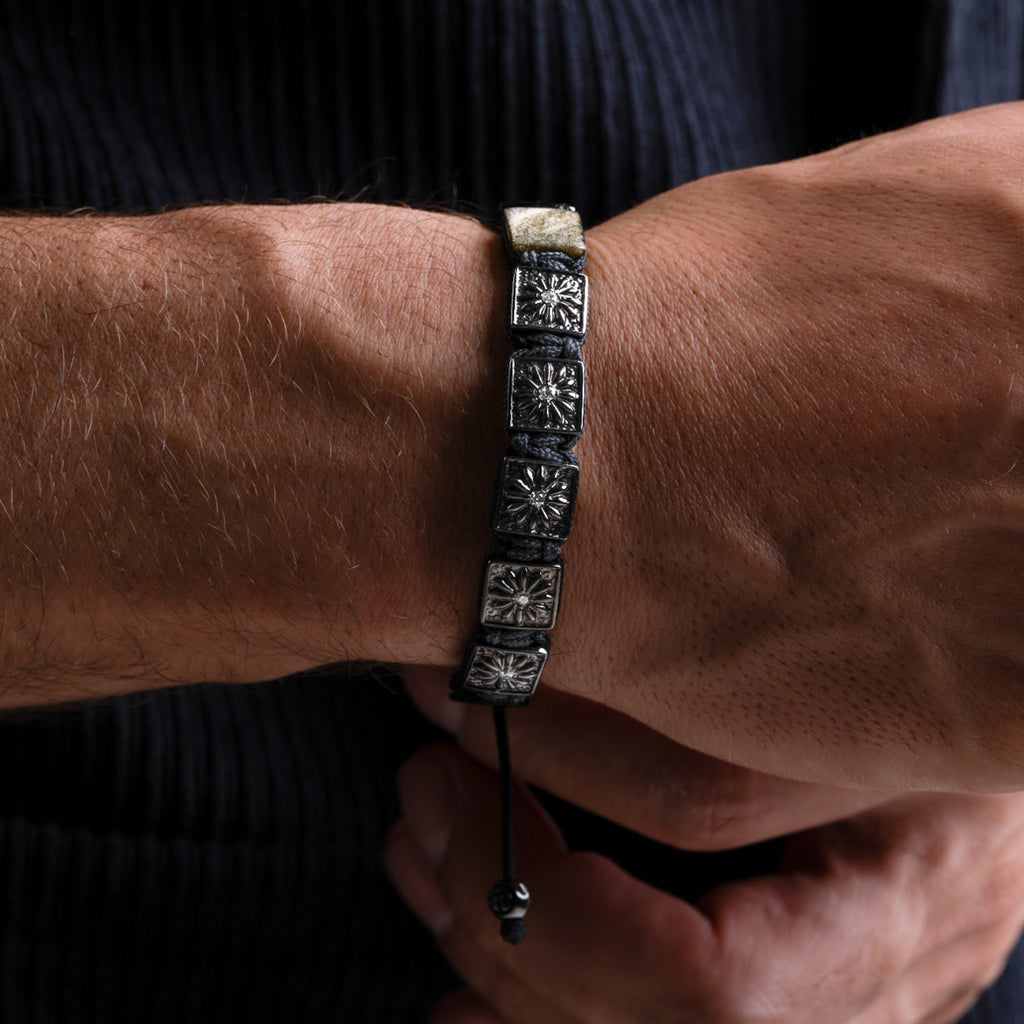 Close-up of a wrist wearing a black beaded bracelet with silver accents.