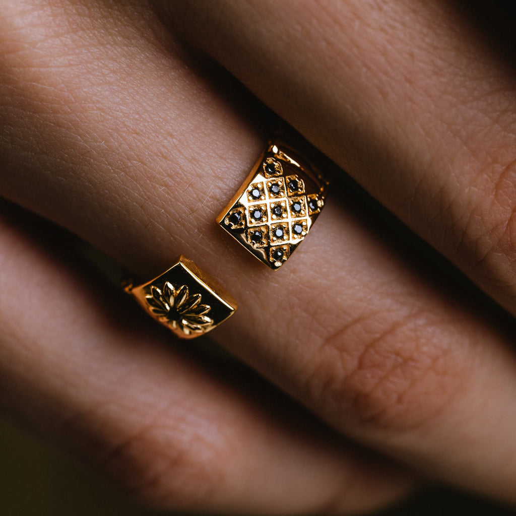 A gold ring with black diamonds on a person's finger