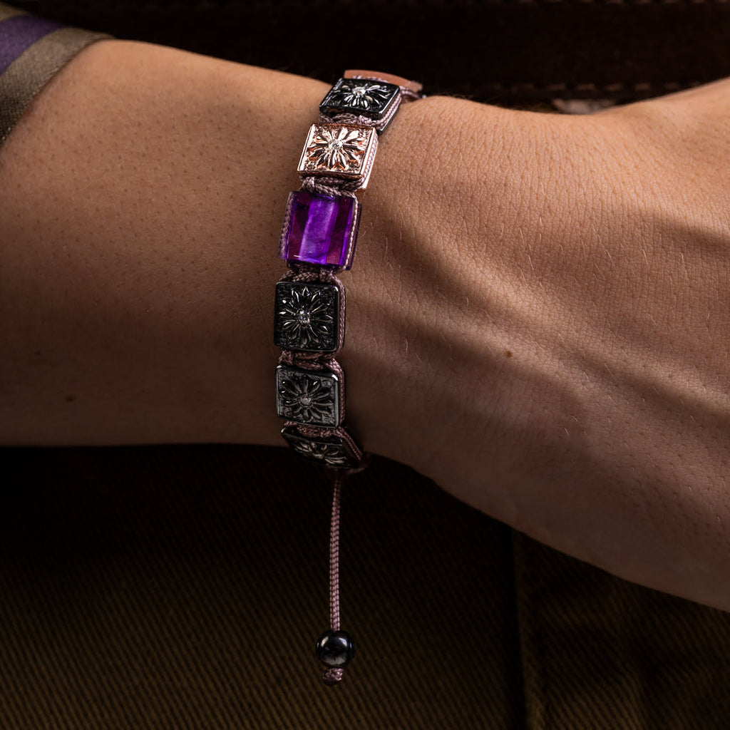 Bracelet with square-shaped gemstones on a wrist against a dark background