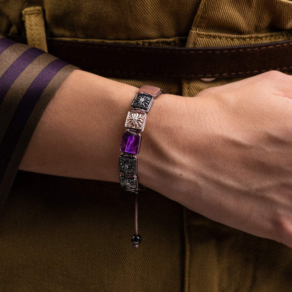 Bracelet with purple gemstone on a wrist against a brown background