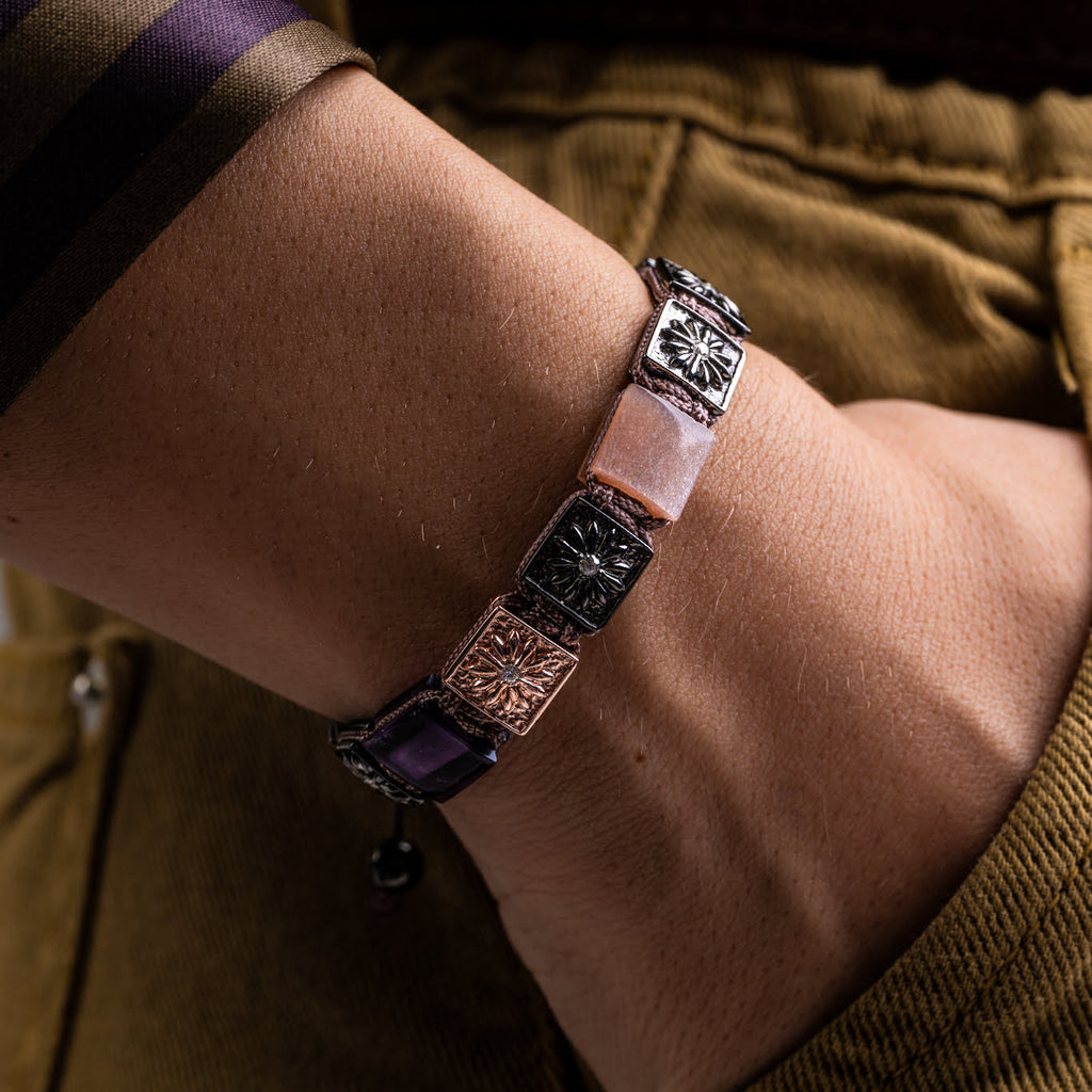 Bracelet with decorative links on a wrist, wearing a brownshirt.