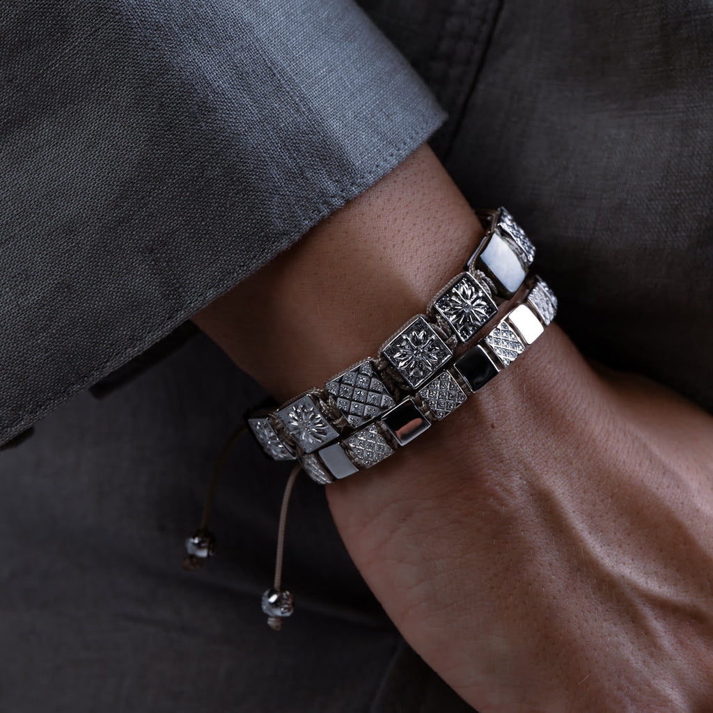 Close-up of a wrist wearing a silver bracelet with intricate designs.