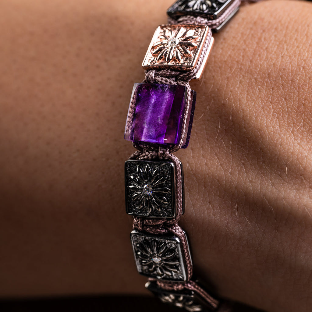 Bracelet with purple gemstone on a wrist against a neutral background