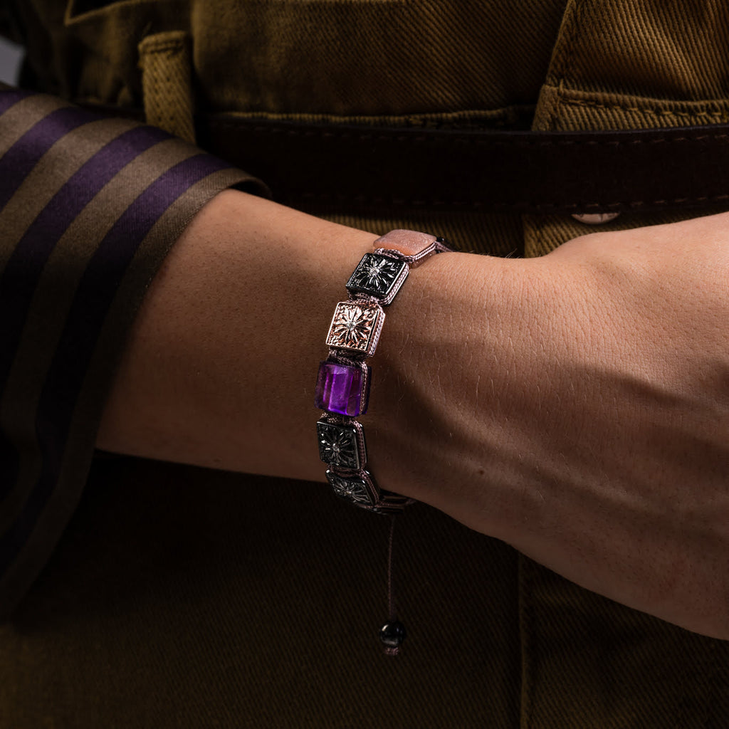Bracelet with purple gemstone worn on a wrist against a brown background