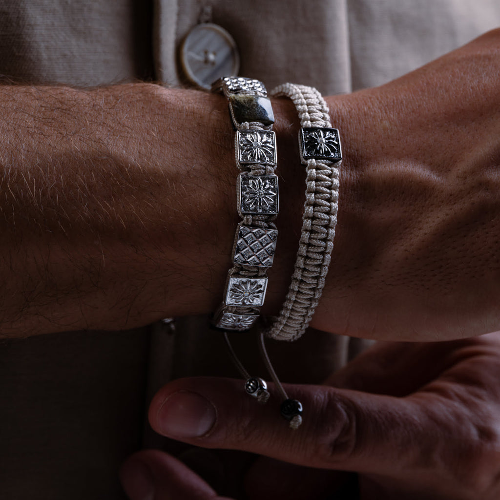 Close-up of a wrist wearing two bracelets with a neutral background