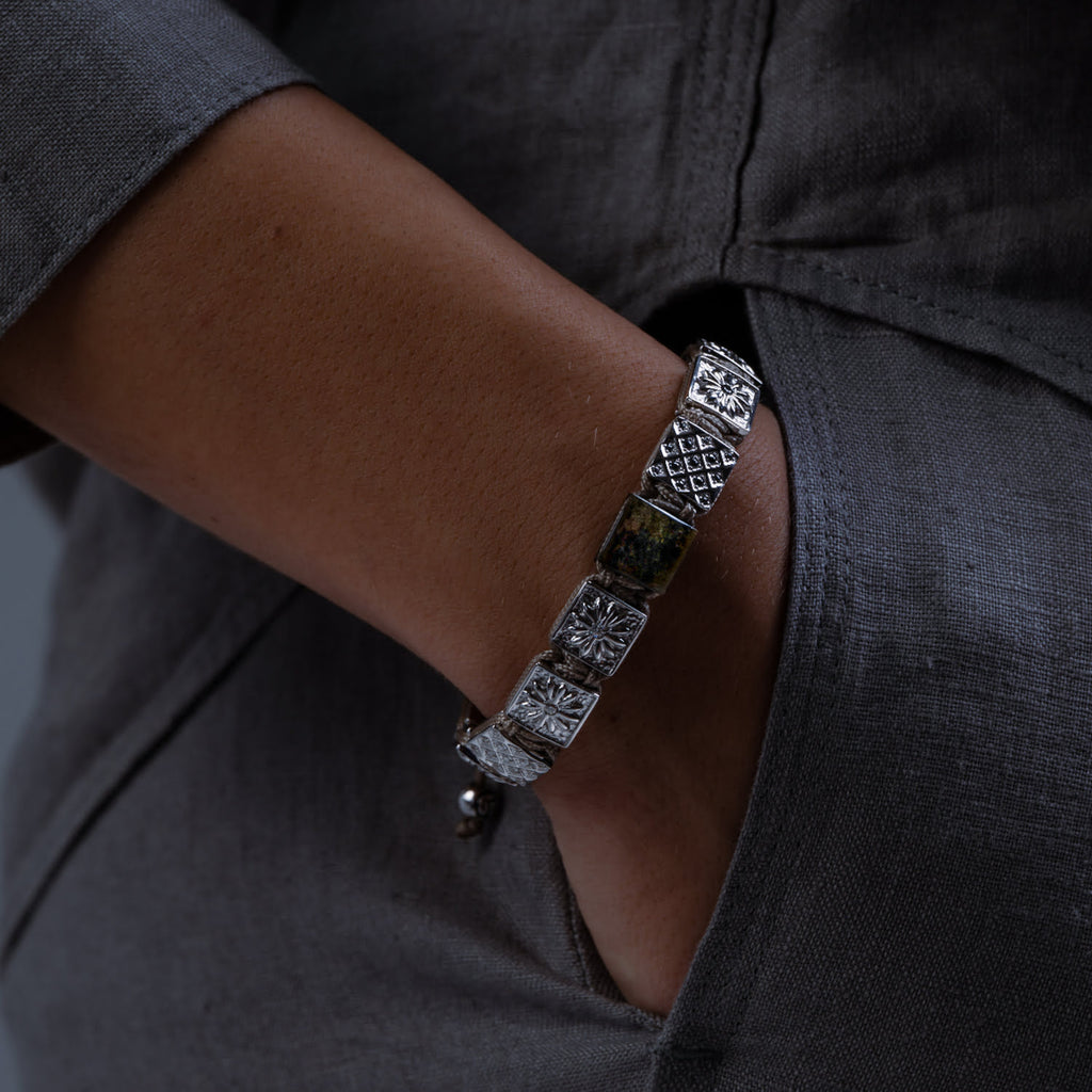 Close-up of a person wearing a silver bracelet with a dark shirt.