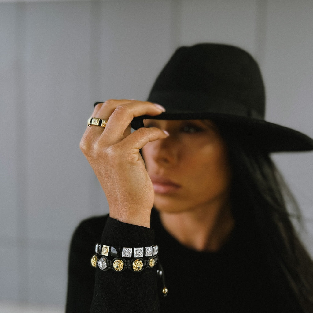 woman in balck outfit wearing black and gold macrame bracelet stack - mahigan jewelry